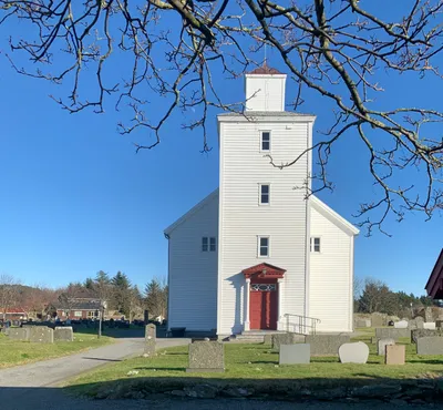 Fremsiden av Falnes kyrkje med kyrkjegarden i forgrunnen
