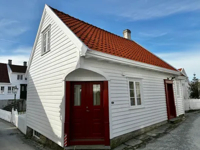 Inngangspartiet til Det klassiske hjørnet. Kvitmalt hus med raud dør og raude takstein